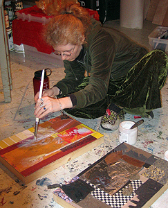 person working on paintings on the floor of her studio