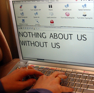 person typing into AAC software on a computer the words NOTHING ABOUT US WITHOUT US