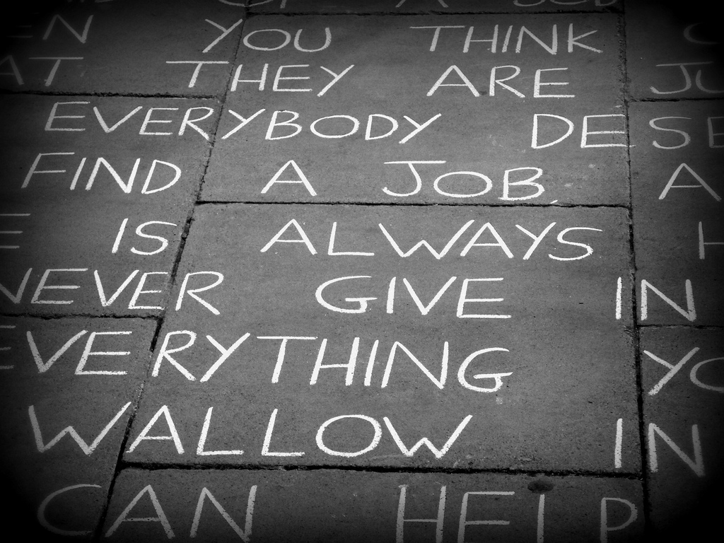 A sidewalk with words written in bold, white chalk.