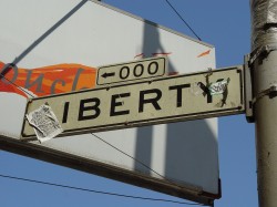 Sign for the "000" block of Liberty street, obscured with debris and stickers.