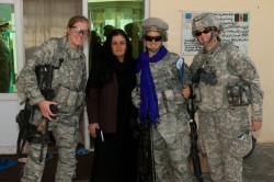 Three U.S. Troops stand with an Afghani woman.