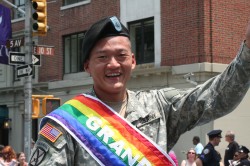 Lt. Dan Choi: A Korean-American man in an Army Lt.'s uniform, draped with a Gay Pride Parade's "Grand Marshall" banner, which is a beautiful rainbow banner.