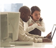 a man and a woman working together over a laptop computer